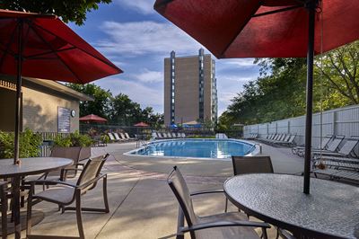 Tables and chairs with umbrellas on pool deck overlooking pool